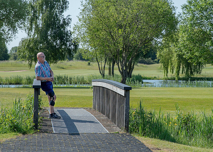 Person mit einer Knieorthese von Össur steht auf einer Brücke Person mit einer Knieorthese von Össur steht auf einer Brücke