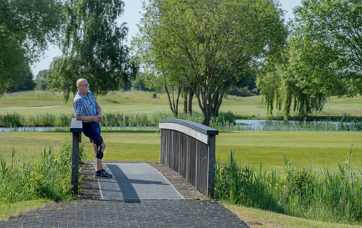 Person mit einer Knieorthese von Össur steht auf einer Brücke Person mit einer Knieorthese von Össur steht auf einer Brücke